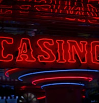 Neon lights display the word 'CASINO' in bright red, standing out against a dark background. The vibrant glow reflects a lively and bustling atmosphere.